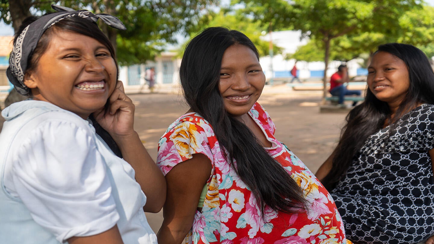 Mujeres Wayúu comparten sonrientes en una plaza 